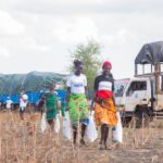 Women participate in a community aid distribution event in a rural setting.