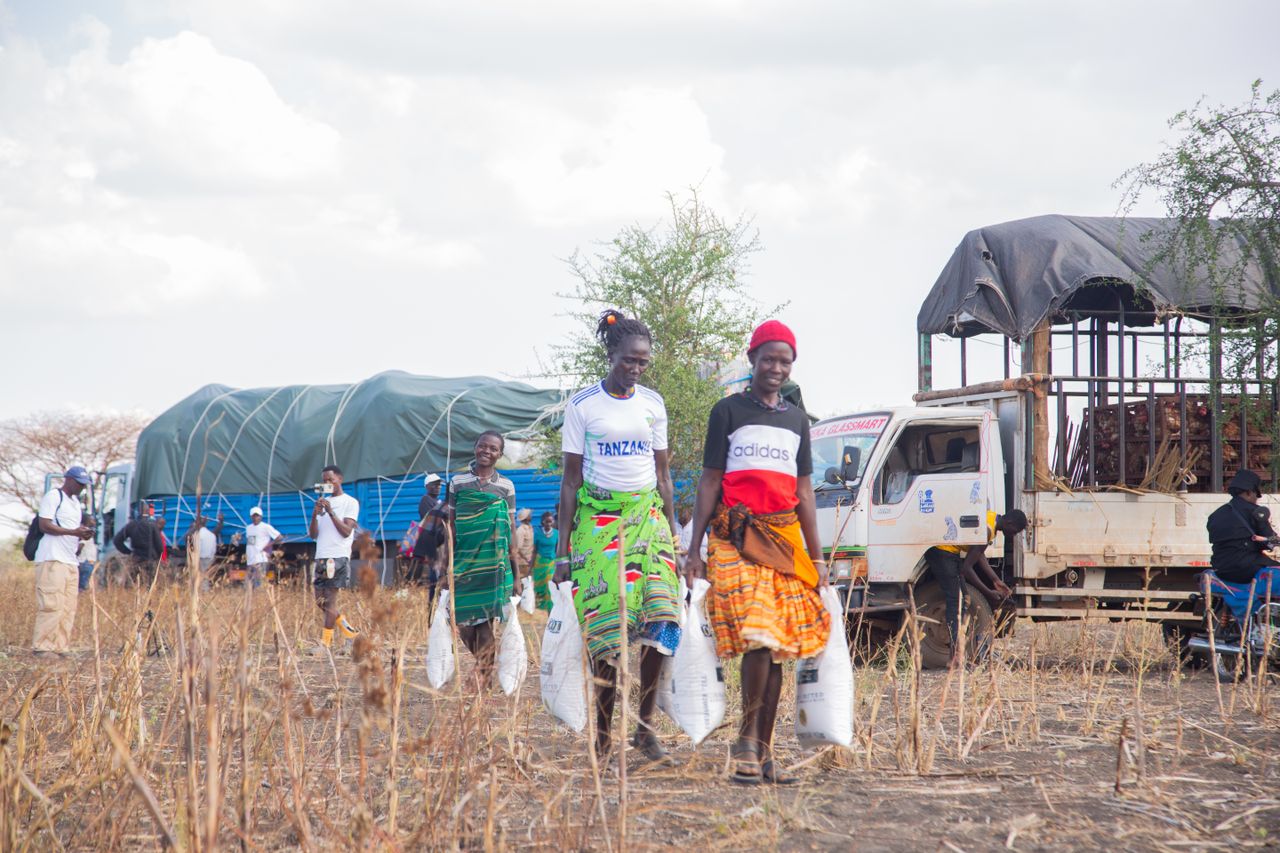 services-01 Women participate in a community aid distribution event in a rural setting.