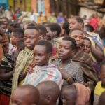 A vibrant street scene showcasing African children in traditional attire at a busy marketplace.