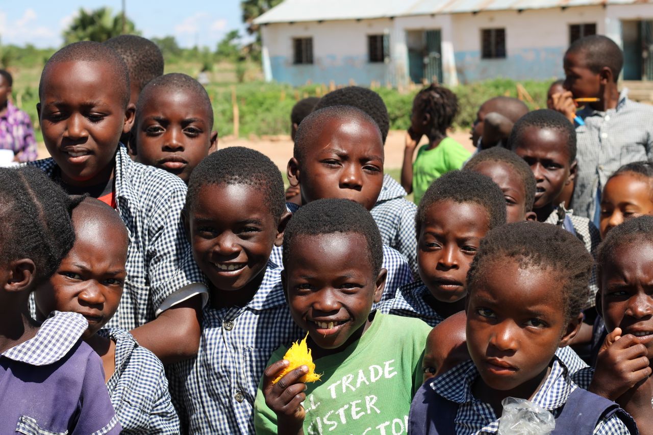 Happy group of children in a Zambian schoolyard on a sunny day.