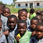Happy group of children in a Zambian schoolyard on a sunny day.